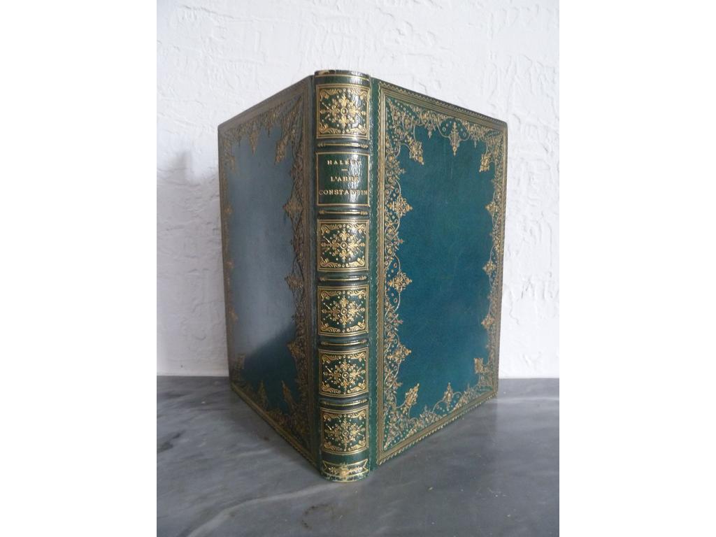 HALEVY, Ludovic. (LEMAIRE, Madeleine) : Labbé Constantin. Paris : Calmann Lévy et Boussod-Valadon, 1888. Un volume grand in-8°. Reliure de lépoque plein maroquin bleu pastiche du XVIIIe , dos à nerfs orné de caissons de double filet doré fleuronnés, roulette filet et belle dentelle dorés en encadrement des plats, filet doré sur coupes, roulette dorée sur chasses, toutes tranches dorées. 37 illustrations de Madeleine LEMAIRE dont vignette sur titre, 9 en-tête et 9 culs-de-lampe, en noir et 18 hors-texte en couleurs. Ex-dono sur feuillet blanc liminaire. Quelques frottis sinon BEL EXEMPLAIRE en reliure pastiche.