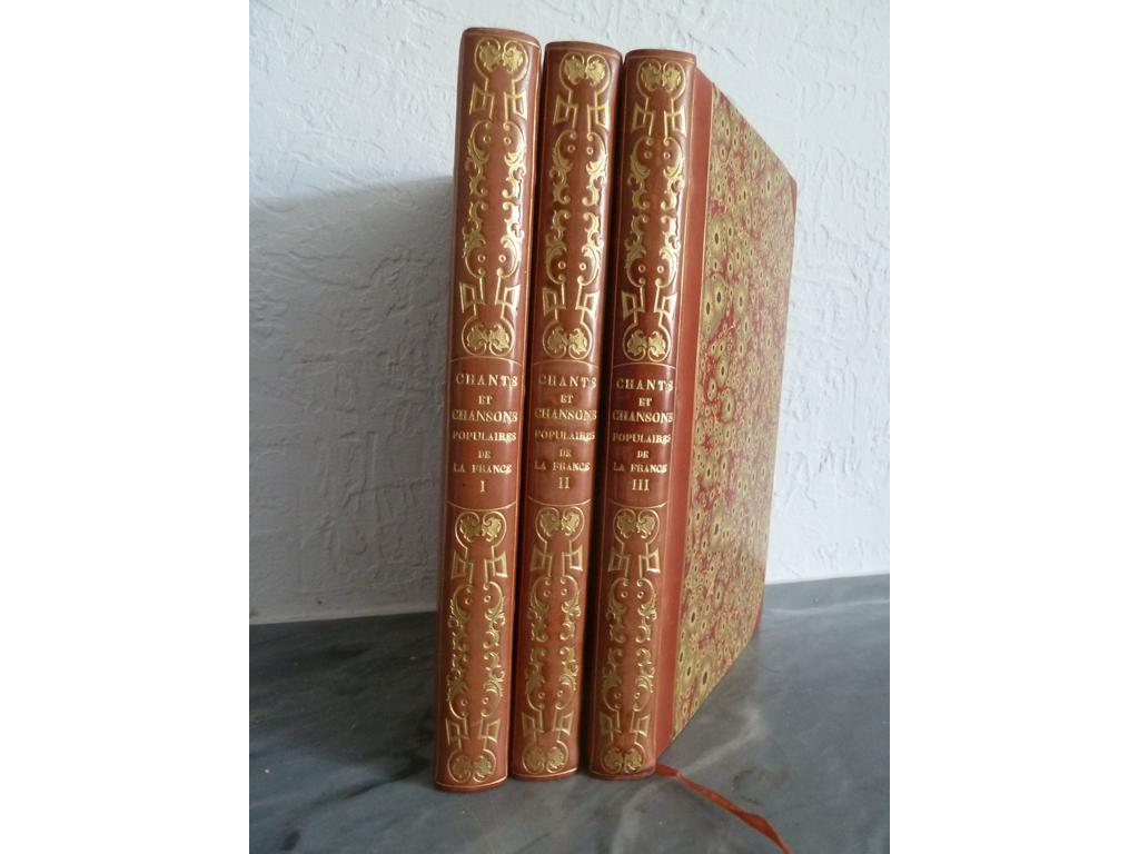 CHANTS ET CHANSONS POPULAIRES DE LA FRANCE. Paris : H. Delloye, 1843-1844. 3 volumes grand in-8°. Reliure circa fin XIXe demi-veau à coins saumon, dos lisses ornés en long de fers romantiques dorés, double filet doré sur les plats, têtes dorées, couvertures illustrées et dos conservés, non rognés. Illustré de 3 titres-frontispices et de très nombreuses vignettes gravées sur bois des meilleurs artistes de lépoque, tels que DAUBIGNY, MEISSONIER, TRIMOLET, STEINHEIL, G. STAAL, EMY, BOILY, DE BEAUMONT. Célèbre ouvrage publié en 84 livraisons, comprenant chacune un texte imprimé de quatre pages avec notice et musique et une partie, de quatre pages également, entièrement gravée, contenant le texte illustré des chansons. TRES BEL EXEMPLAIRE de cette admirable publication complète de ses fort belles couvertures illustrées en parfait état (Carteret, III, p. 150 : « parmi les plus belles des illustrés du 19e siècle »)., lavé et encollé et recouvert de séduisantes reliures de style romantique.