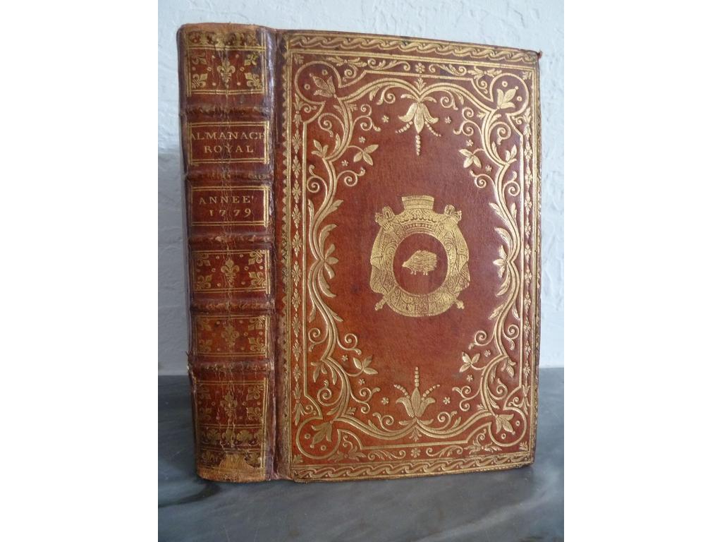Almanach royal, année 1779 présenté à sa Majesté. Paris : Le Breton, s.d. (1779). Un volume in-8°. Reliure de lépoque plein maroquin grenat, dos à nerfs ornés de caissons de double filet doré avec fleur de lys dorée au centre et aux écoinçons, plats ornés dune plaque dorée attribuée à Pierre-Paul DUBUISSON à décor mêlant feuillages et grandes fleurs à pistils, avec armes dorées au centre du Chancelier de MAUPEOU, filet doré sur coupes, roulette dorée hachurée sur chasses doublure et gardes de tabis bleu, toutes tranches dorées. (Galantaris : Manuel.. 284 planche 10. Rahir : K). Quelques frottis et rousseurs, couleur du 1er plat tendant vers le havane. BEL EXEMPLAIRE.
