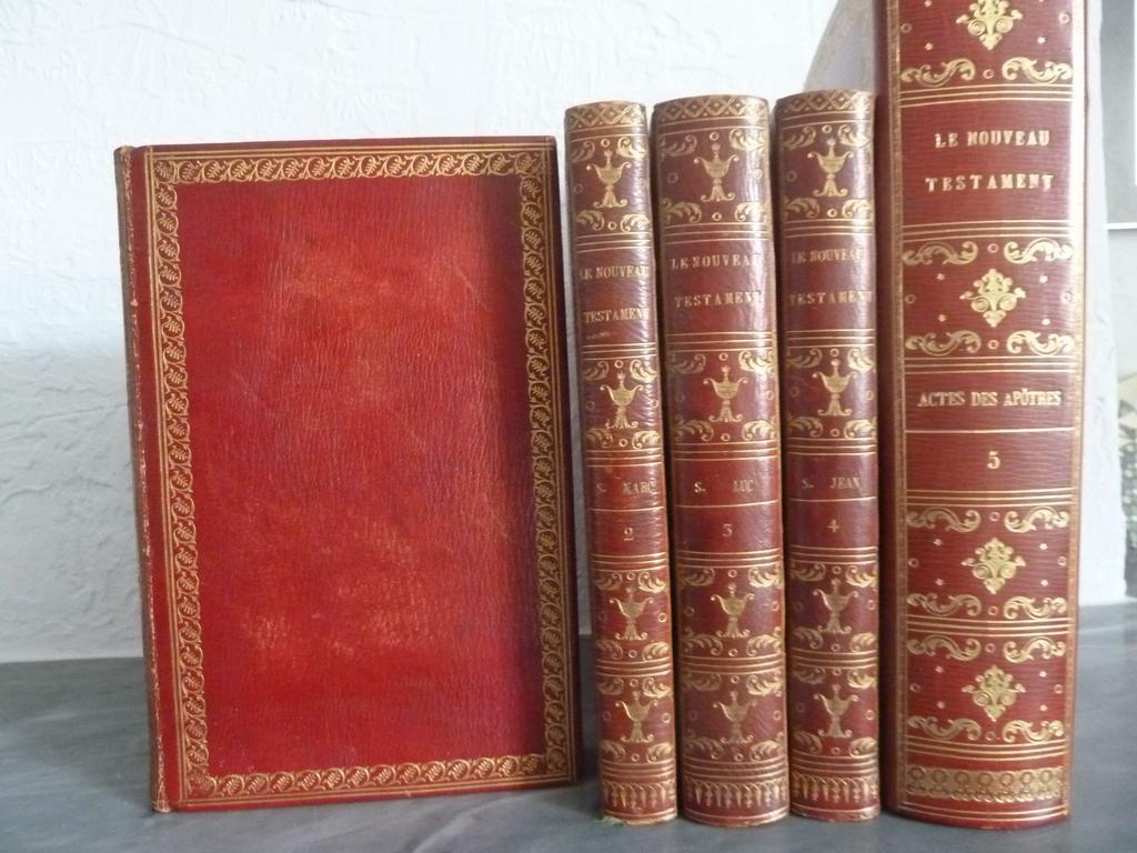 SACY : Le nouveau testament en latin et en français, traduit par Sacy. Paris : Didot Jeune, 1793 et 1798. 4 volumes grand in-8° et 1 volume petit in-4°. Reliures plein maroquin rouge de lépoque. Pour les 4 volumes in-8° : dos lisses ornés de triple filet doré en place des nerfs, avec aux entre-nerfs, pot couvert et rinceaux dorés, double filet doré bordant une belle roulette dorée de pampres en encadrement des plats, double filet doré sur coupes, roulette dorée sur chasses, toutes tranches dorées. Reliures signées par COURTEVAL. Pour le 5ième volume, plus grand et avec décor différent, reliure circa 1810-1820 plein maroquin rouge, dos lisse orné de triple filet doré en place des nerfs avec rinceaux et fleurons dorés, double filet doré bordant une belle frise doré en encadrement des plats, double filet doré sur coupes, roulette dorée sur chasses, tête dorée. Les gardes et les feuillets blancs initiaux semblent postérieurs. Reliure non signée mais de grande qualité. Illustré de 5 frontispices et 107 (sur 108, un hors-texte manque au Tome IV) gravures hors-texte de MOREAU, gravés par Baquoy, Dambrun, Delaunay, Delignon, Halbon, Petit,  (29+12+26+17+28).Le 5ième volume qui est paru quelques années plus tard, est ici bien présent. Il est plus grand de marges et comme indiqué supra dans une reliure légèrement postérieure et non signée. Il est bien daté de 1798 avec quelques gravures datées de 1801. (Cohen : 756). TRES BEL EXEMPLAIRE, en plein maroquin signée par Courteval, fort bien conservé.