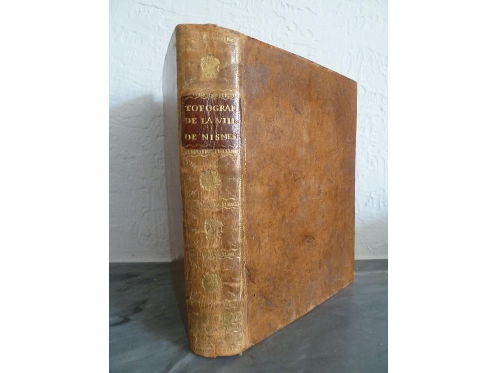 VINCENS et BAUMES : Topographie de la ville de Nismes et de sa banlieue. Nismes : Veuve Belle, an X (1802). Un volume in-4°. Reliure de lépoque pleine basane havane, dos lisse orné de roulettes et fers spéciaux dorés, pièce de titre en maroquin rouge, roulette dorée sur coupes.  Bien complet de son tableau dépliant et de sa planche gravée hors-texte. Menus défauts. BEL EXEMPLAIRE.