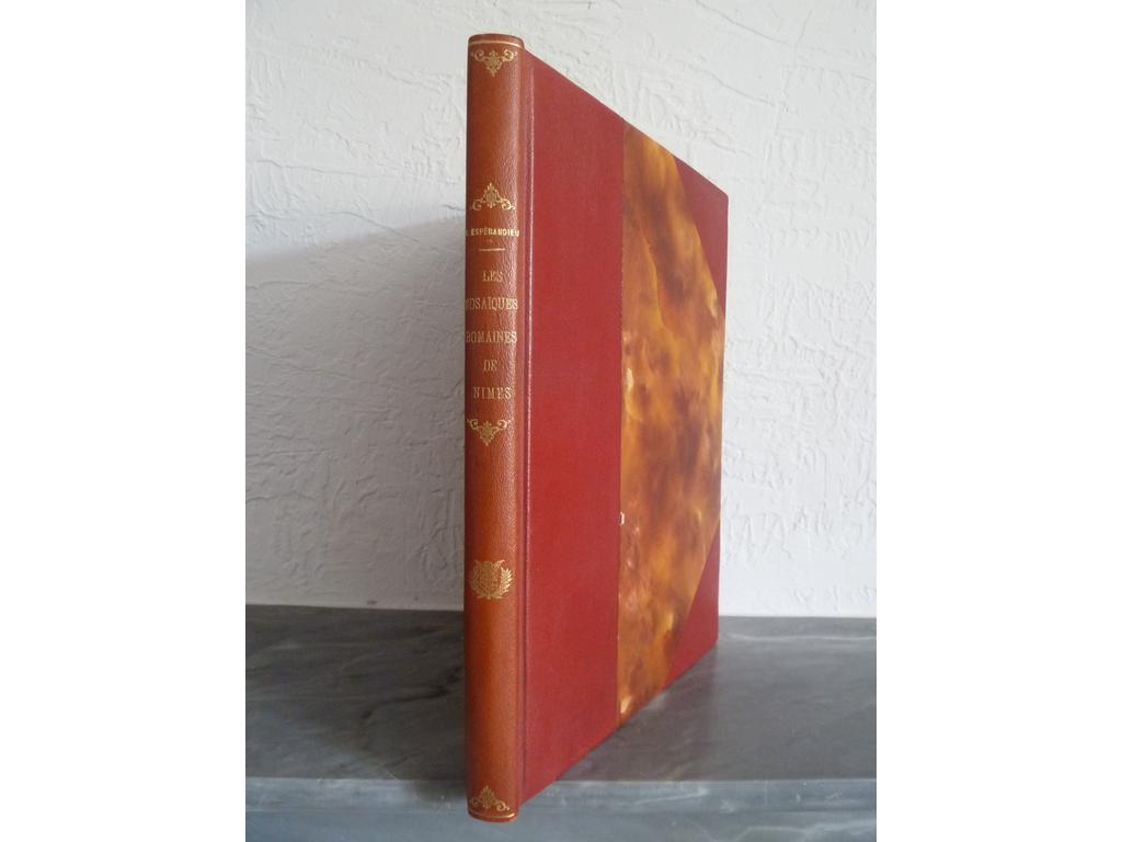 ESPERANDIEU, Emile : Les mosaïques romaines de Nîmes. Mîmes : Editions méridionales, 1935. Un volume grand in-4°. Reliure de lépoque demi-chagrin rouge à coins à la bradel, dos lisse orné. Couvertures imprimées conservées, non rogné. Illustré dun blason en couleurs appliqué en tête, de 16 reproductions en noir à pleine page, 21 in-texte en noir et bien complet de ses 25 planches à pleine page dont 2 à double page en couleurs. Dos un brin éclairci sinon TRES BEL EXEMPLAIRE.