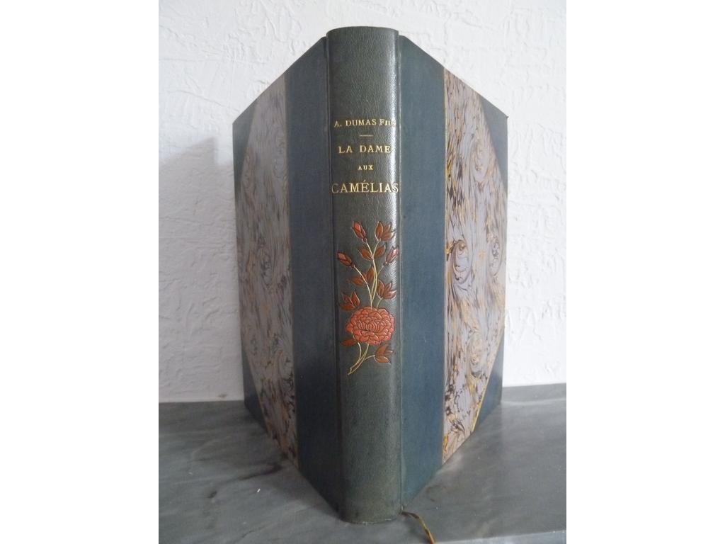DUMAS, Alexandre. (LYNCH, A.) : La dame aux camélias. Paris : Quantin, s.d. (circa 1887). Un volume grand in-4°. Reliure demi-chagrin bleu vert à coins, dos lisse orné au centre dune composition florale mosaïquée en maroquin orangé et grenat, double filet doré sur les plats, tête dorée, couvertures conservées. Illustré de 11 eaux-fortes dont frontispice et 10 hors-texte et de 31 in-texte en héliogravures sauf la vignette sur titre en eau-forte dA. LYNCH.  Exemplaire sur vélin simili japon. Dos un brin plus clair, quelques menus défauts sinon BEL EXEMPLAIRE.