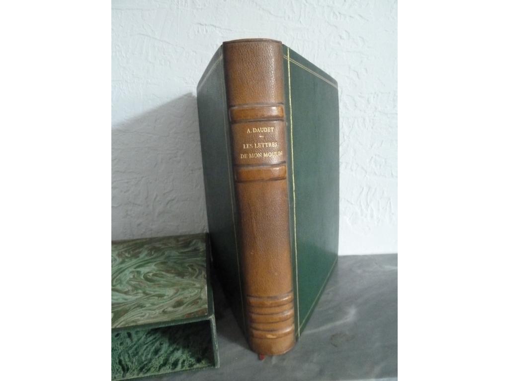 DAUDET, Alphonse. (GUIRAUD, Geneviève) : Les lettres de moulin. S.l. : Le cercle des bibliophiles, Portal et Cie, 1946. 1 volume in-4°. Reliure de lépoque plein chagrin verts, dos à 5 nerfs sautés janséniste, double filet doré en encadrement des plats, triple filet doré sur chasses. Couvertures illustrées et dos conservés. Non rogné. Etui bordé assorti. Bien complet de ses gravures sur cuivre de Geneviève GUIRAUD dont frontispice, une vignette sur 1ère de couverture et une autre sur titre, et 25 à pleine page. Tiré à 290 ex. numérotés sur vergé Montval à la cuve. 1 des 200. Dos ayant viré au marron sinon BON EXEMPLAIRE.