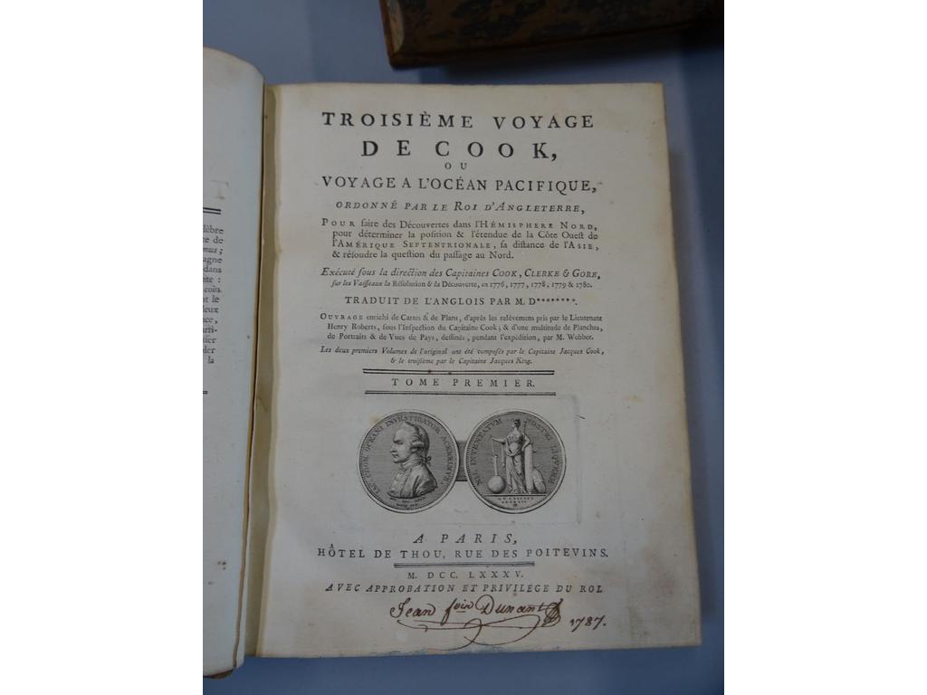 COOK, James : Troisième voyage de Cook, ou voyage à locéan Pacifique, ordonné par le Roi d'Angleterre  Exécuté sous la direction des Capitaines Cook, Clerke   Gore, sur les vaisseaux la Résolution   la Découverte, en 1776, 1777, 1778, 1779 à 1780. Paris : Hôtel de Thou, 1785. 4 volumes in-4°. Reliures de lépoque plein veau fauve, dos à nerfs ornés de caissons de double filet doré, pièces de titre et de tomaison en maroquin rouge, triple filet doré en encadrement des plats, filet doré sur coupes, toutes tranches marbrées. Lillustration que lon trouve souvent dans un atlas à part a été ici interfoliée et se compose de 88 planches. Notre exemplaire en contient 86 (le frontispice et la carte générale manquent) soit 25 cartes, plans ou coupes dont 20 dépliantes, 14 superbes portraits, et 47 vues, cérémonies ou ustensiles dont 37 dépliantes. 1 tableau dépliante dappendice in-fine. Ex-libris à lencre du XVIIIe. Quelques cahiers brunis, quelques usures aux reliures néanmoins TRES BEL EXEMPLAIRE, bien conservé à la fascinante et emblématique illustration.